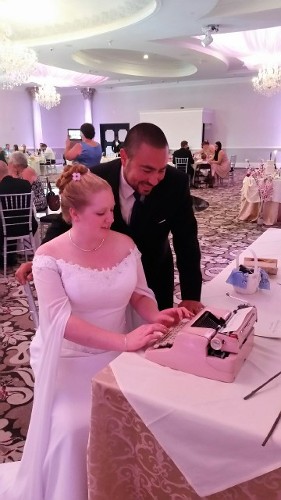 Bride Typing on Pink Typewriter at Wedding Reception